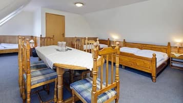 Una habitación con una mesa de comedor de madera, sillas y una cama con cabeceros de madera.