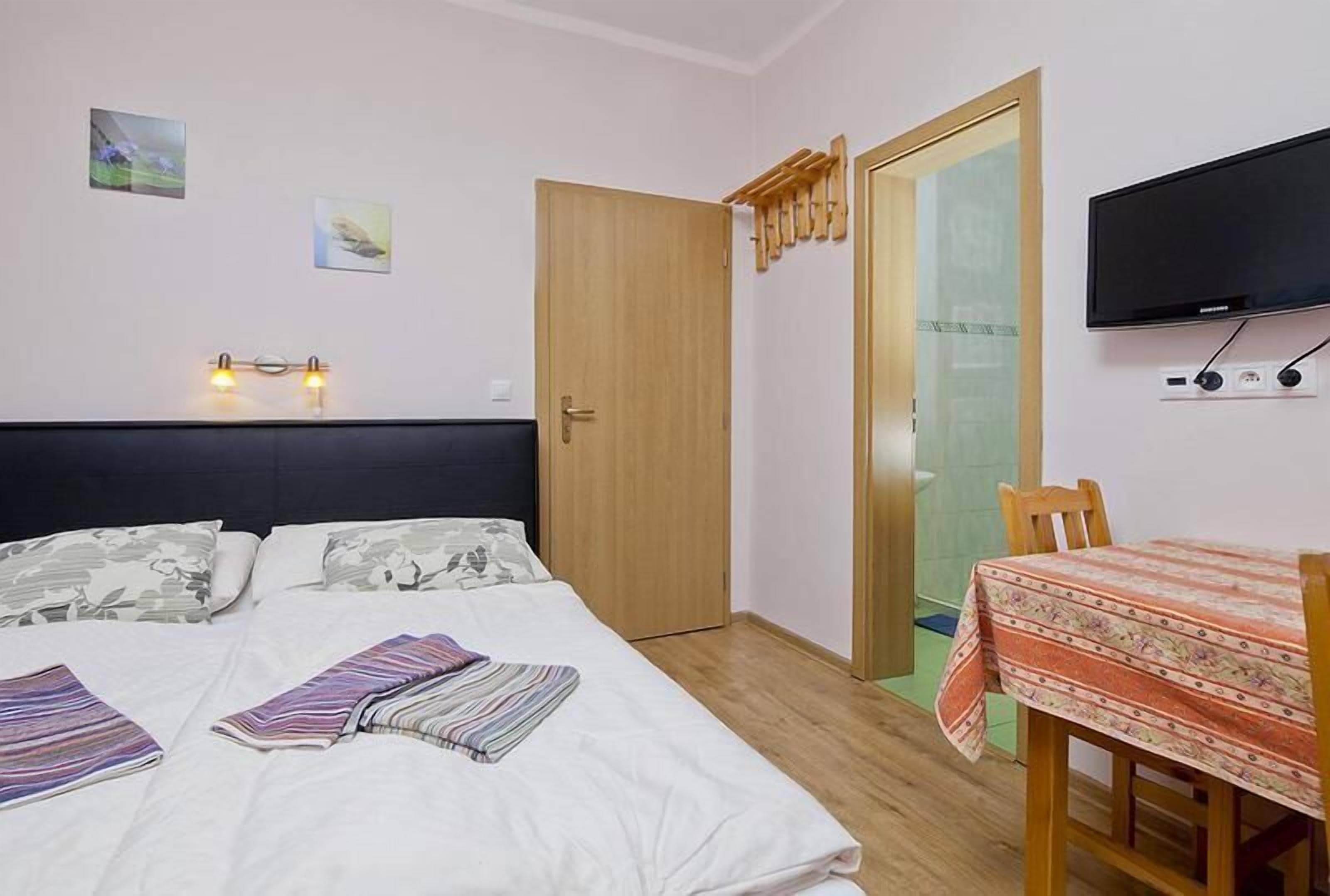 A bedroom with a bed, a TV, a desk, and a chair.
