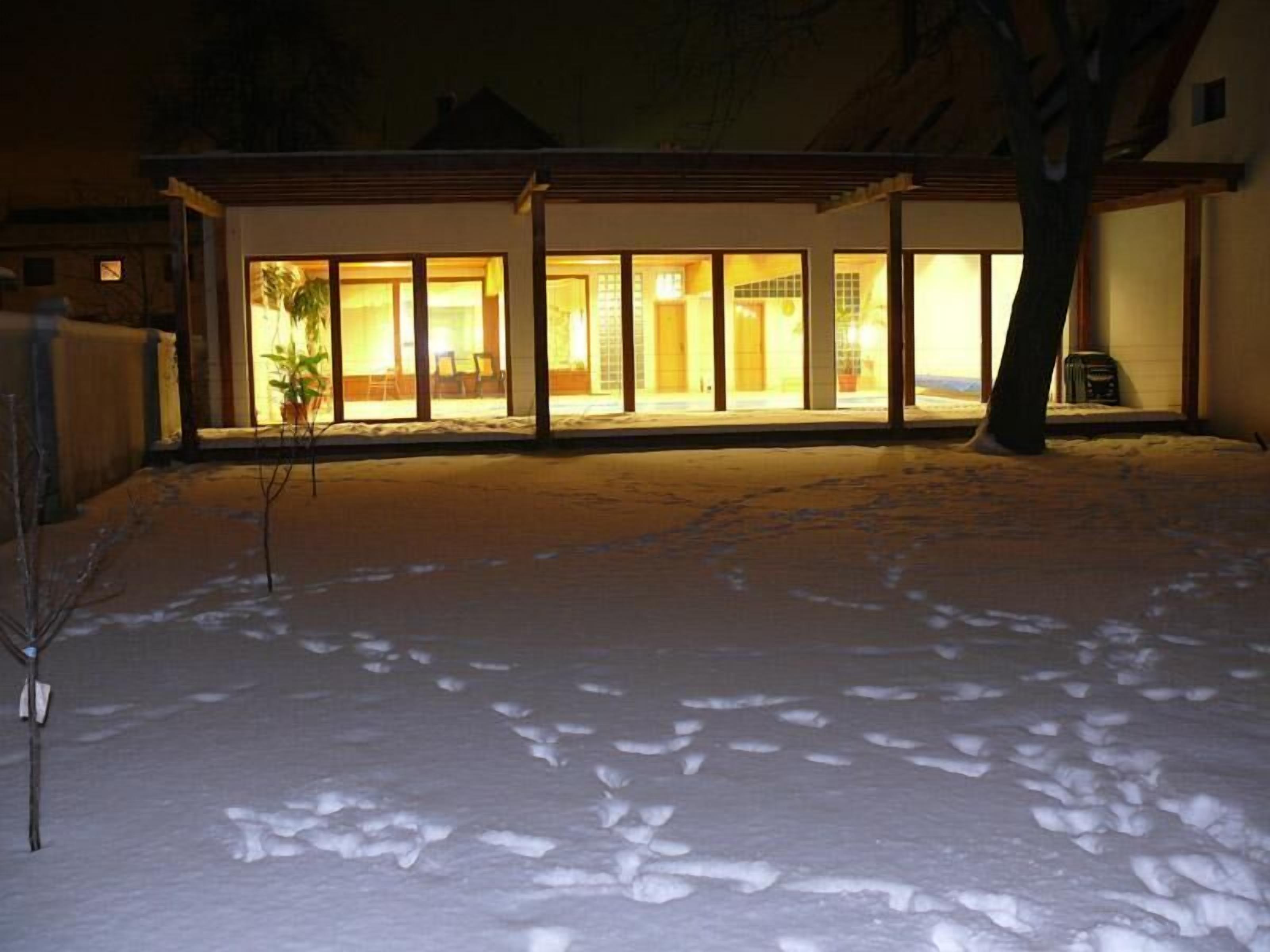 A house with large glass windows and a snow-covered yard.