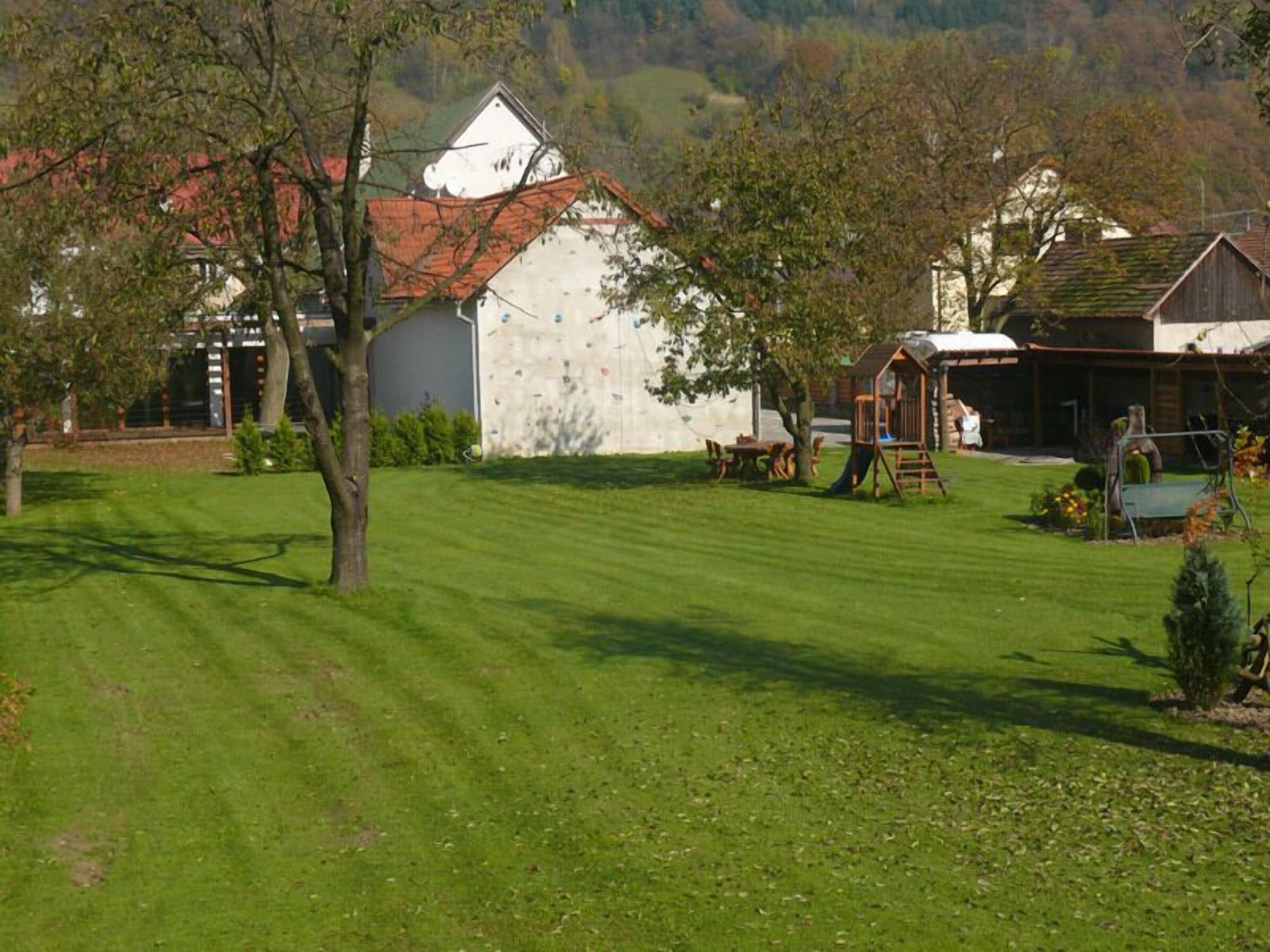 A rural property with a well-maintained lawn, a climbing wall, and a wooden playhouse.