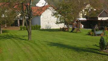 A rural property with a well-maintained lawn, a climbing wall, and a wooden playhouse.