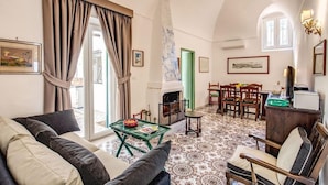 A cozy living room with a fireplace, comfortable seating, and a dining area. - Villa I Magi (Anacapri)