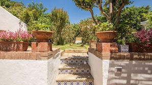 A set of stairs leading to a garden area with terracotta pots and flowering plants. - Villa I Magi (Anacapri)