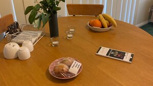 Ein runder Holztisch mit Obstschale, Topfpflanze, Salzstreuern, einem Teller mit Muffins und einer Speisekarte.