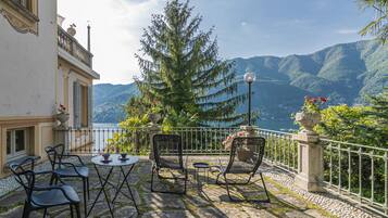 Une terrasse avec des sièges extérieurs, une vue sur le lac et des montagnes en arrière-plan.
