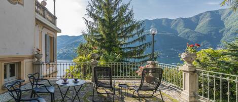 Una terraza con mobiliario exterior, vista al lago y montañas al fondo.