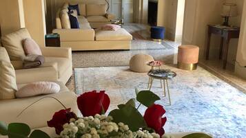 A living room with a sofa, a coffee table, and a vase of red roses.