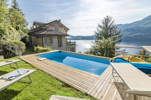 Una piscina al aire libre, sombrillas, sillones reclinables de piscina