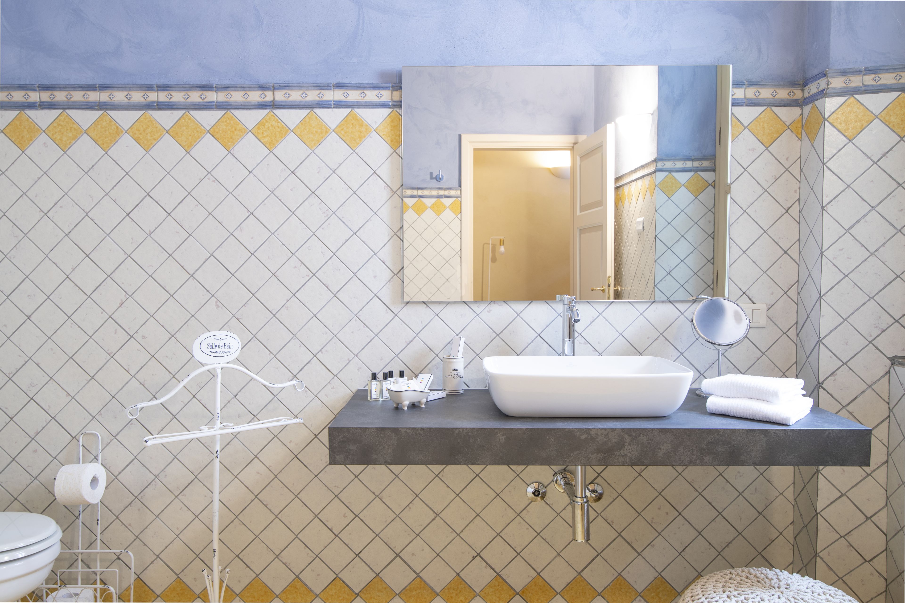 A bathroom with a white sink, mirror, and towel rack.