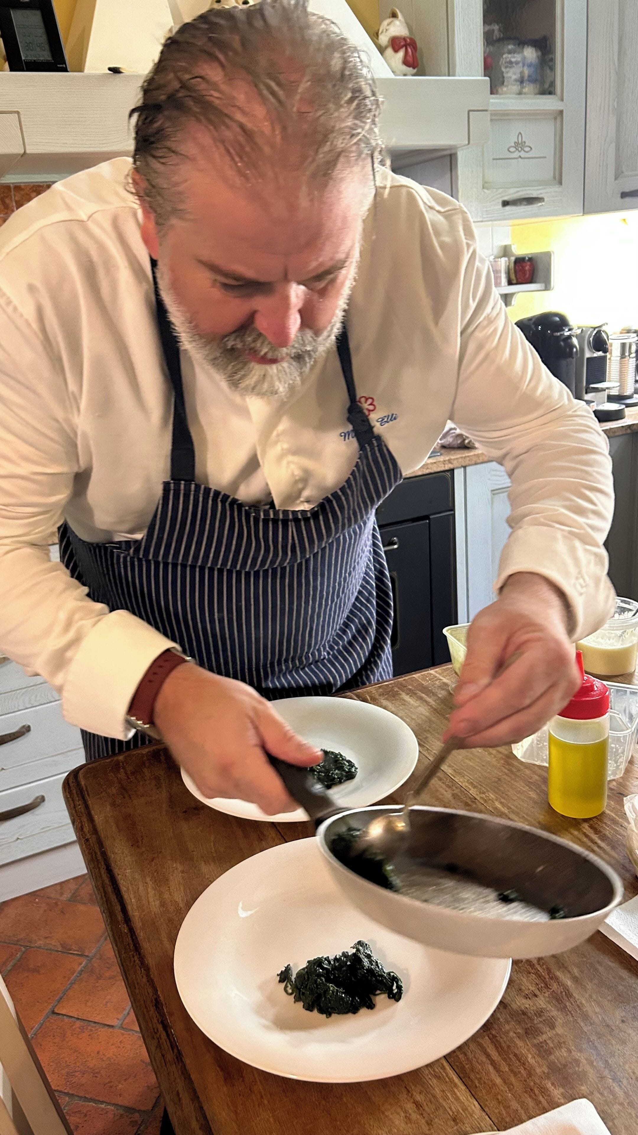 A person cooking at a kitchen counter with a pan, a plate, and a bottle of sauce.