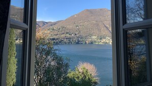 Vista a través de una ventana de un lago rodeado de colinas y vegetación escasa.