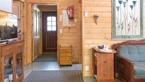 Ein Holzinterieur mit Fernseher, einer Couch, einem Holzkabinett und einer Tür zu einem anderen Raum.