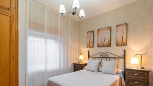 A bedroom with a bed, two bedside tables with lamps, a chandelier, and three wall-mounted paintings. - Villa San Vicente by Interhome (Córdoba/Baena)