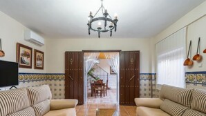 A living room with two sofas, a TV, a chandelier, and a tiled floor. - Villa San Vicente by Interhome (Córdoba/Baena)