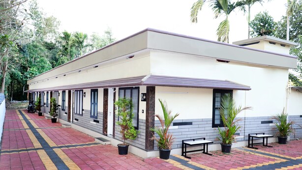 A building with a tiled walkway, potted plants, and outdoor seating. - City Holidays - Wayanad (Sulthan Bathery)