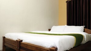 A single bed with a wooden frame, white bedding, and a green accent. - City Holidays - Wayanad (Sulthan Bathery)