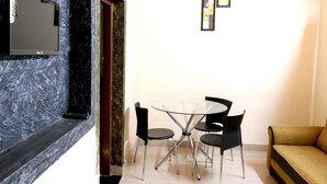 A modern living room with a glass-top coffee table, black chairs, and a yellow sofa. - City Holidays - Wayanad (Sulthan Bathery)
