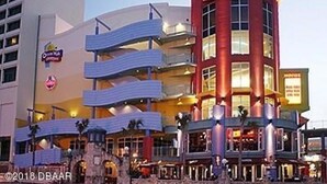 Un hotel de varios pisos con una fachada destacada en rojo y blanco, varios balcones y una señal visible para 'Motel 10'.