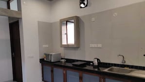 A kitchen with a dark countertop, a built-in sink, and a window above the sink. - The Paperflower - A Wandertrails Stay (Puducherry)