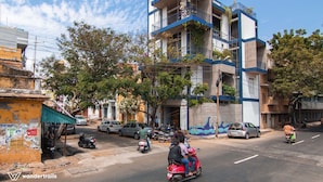 A multi-story building with balconies and a street in front. - The Paperflower - A Wandertrails Stay (Puducherry)