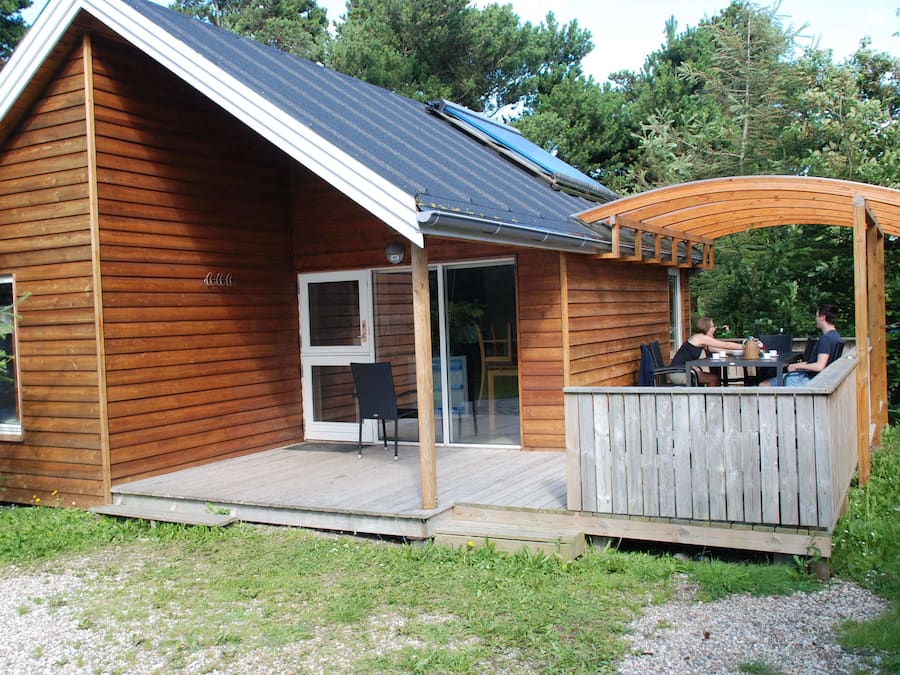 Una cabaña de madera con terraza y zona de estar al aire libre techada.