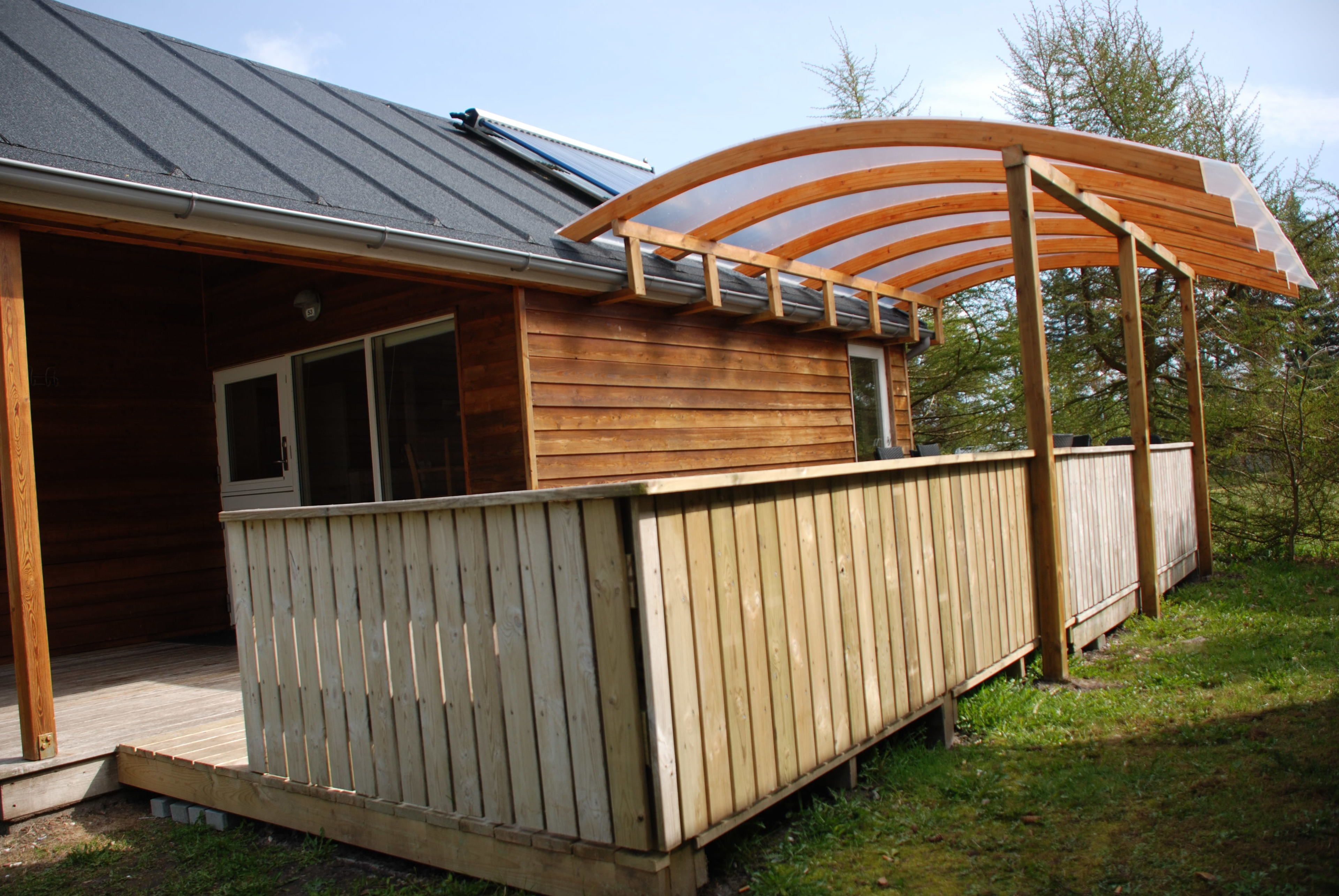 A wooden cabin with a covered deck and a large window.