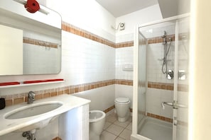 Een badkamer met een wastafel, toilet, douche en bidet.
