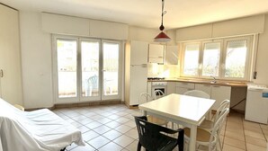 A compact kitchen with a dining table and chairs, a small oven, and a refrigerator.