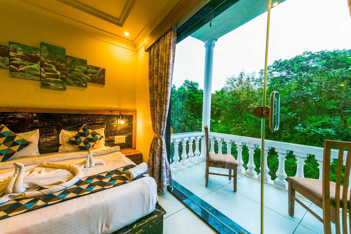A bedroom with a bed, a chair, and a balcony with a railing.