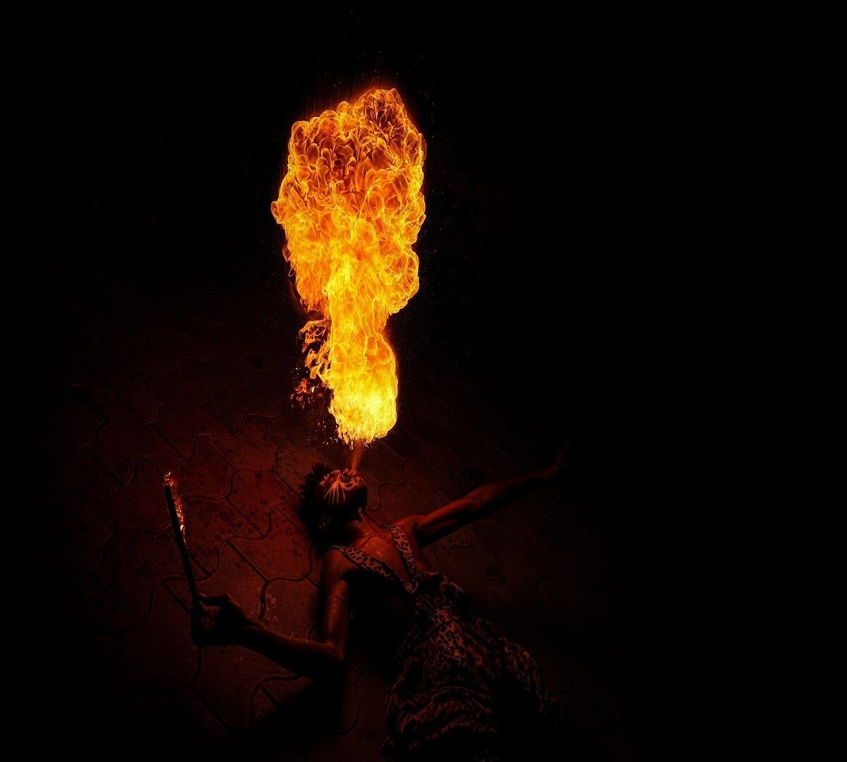 A person performing a fire act with a large flame above their head.