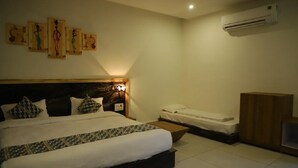 A bedroom with a large bed, a smaller bed, an air conditioner, and a wooden cabinet. - Van Vihar Farm & Resort (Talala)