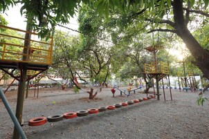 A playground with tire swings, climbing structures, and a fenced area.
