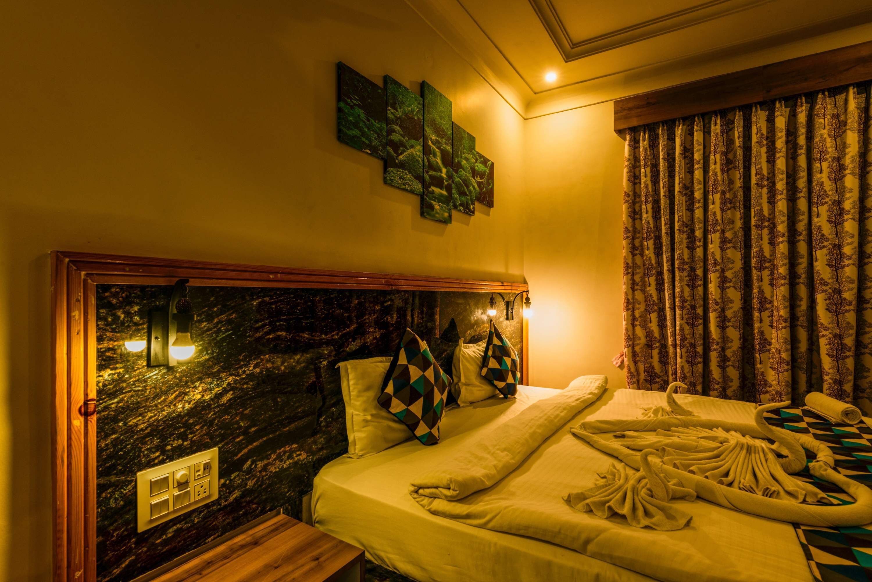 A hotel room with a marble headboard, a bed with a white comforter and pillows, a wooden nightstand, and a wall-mounted light fixture.