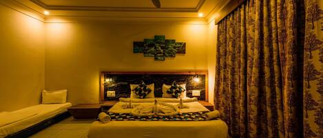 A hotel room with a large bed, a ceiling fan, a decorative wall piece, and patterned curtains.