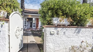 Una entrada tancada amb reixa a una propietat que presenta un mur exterior blanc, una placa amb un número i una porta amb pany de seguretat.