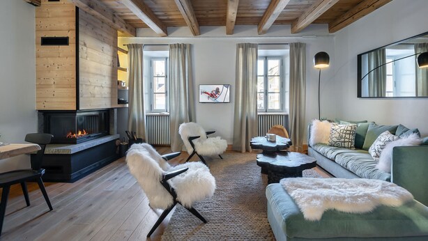 Una sala de estar acogedora con chimenea, vigas de madera, un sofá, una silla y una mesa de centro.