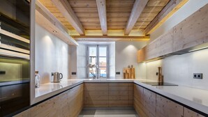 Una cocina moderna con armarios de madera, una isla central y vistas al exterior a través de un amplio ventanal.