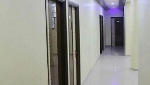A corridor with doors on the left, a light-colored floor, and a door at the end. - Iroomz VKG Complex (Bijapur)