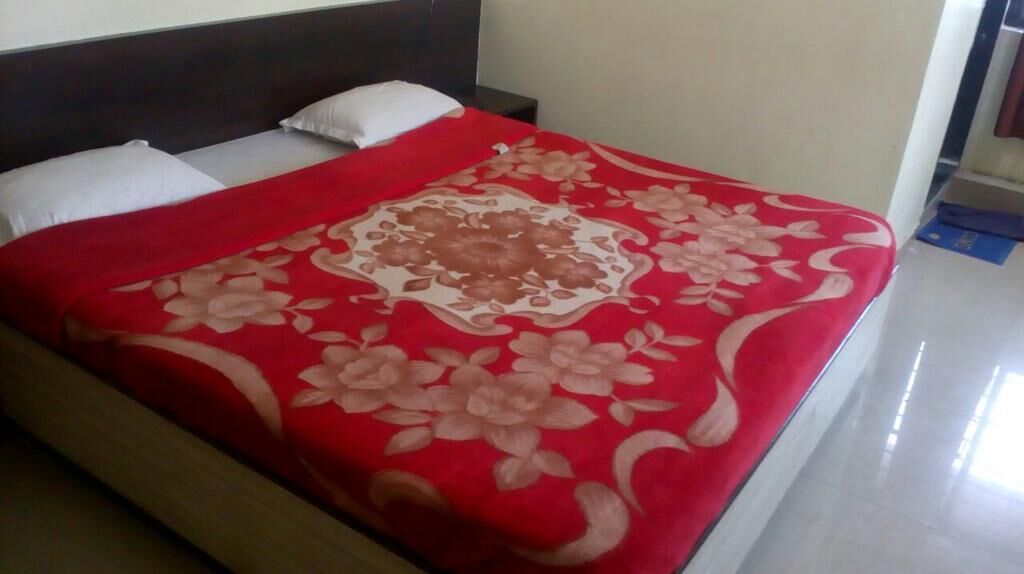 A bed with a red floral bedspread and white pillows.