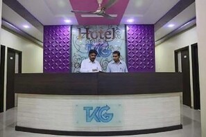 A reception desk with a logo and two staff members. - Iroomz VKG Complex (Bijapur)