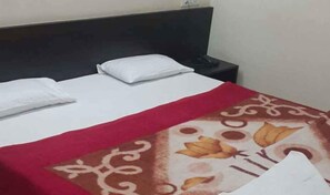 A neatly made bed with a white pillow and a red and brown patterned blanket. - Iroomz VKG Complex (Bijapur)