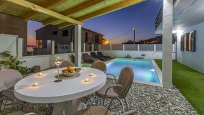 An outdoor patio with a round table, chairs, candles, and a pool. - Perfectly located holiday home with a private pool (Stanici, Omiš)