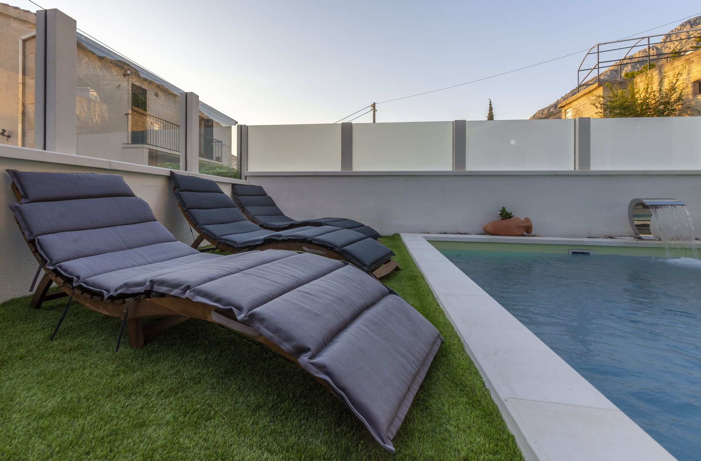 Un espace piscine comprenant trois chaises longues et un petit élément décoratif aquatique.