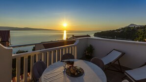 A terrace with a table set for two, overlooking a body of water and a distant mountain range during sunset. - Perfectly located holiday home with a private pool (Stanici, Omiš)
