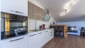 A modern kitchen with a built-in oven, a dining area with a table and chairs, and a seating area with a sofa and a coffee table. - Perfectly located holiday home with a private pool (Stanici, Omiš)