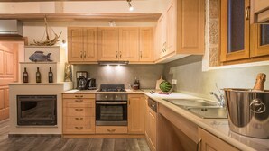 A modern kitchen with wooden cabinets, a built-in oven, a microwave, and a stainless steel sink.
