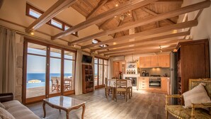 A spacious living area with a large wooden ceiling, a dining set, and a kitchen area.
