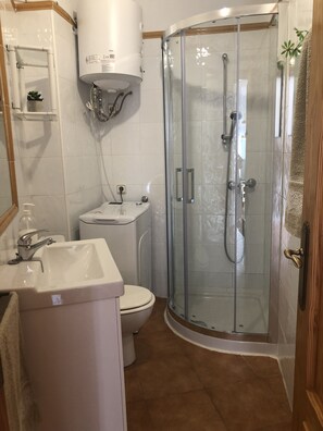 Een badkamer met toilet, wastafel en douchecabine.