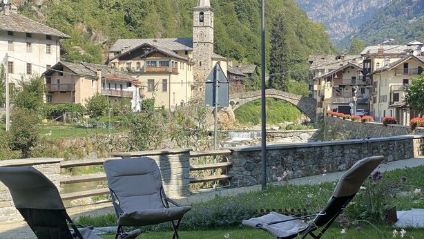 A grassy area with two chairs, a stone bridge, and a mountain backdrop. - VALLEY OF GRESSONEY FONTAINEMORE TRILOCALE (Fontainemore)