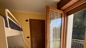 A room with a bunk bed, a door leading to a balcony, and a tiled floor. - VALLEY OF GRESSONEY FONTAINEMORE TRILOCALE (Fontainemore)